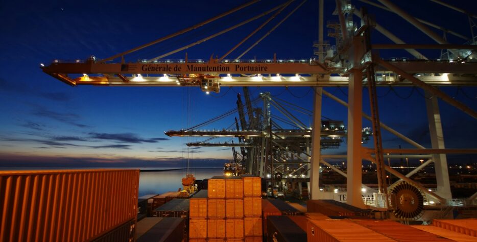 a cargo ship is docked at night with its lights on